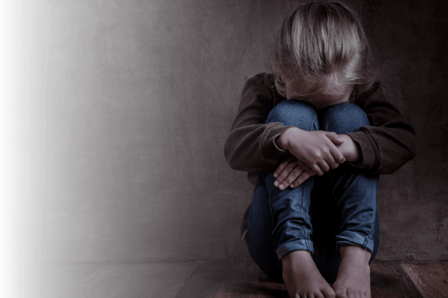 Trauriges Mädchen sitzt an der Wand