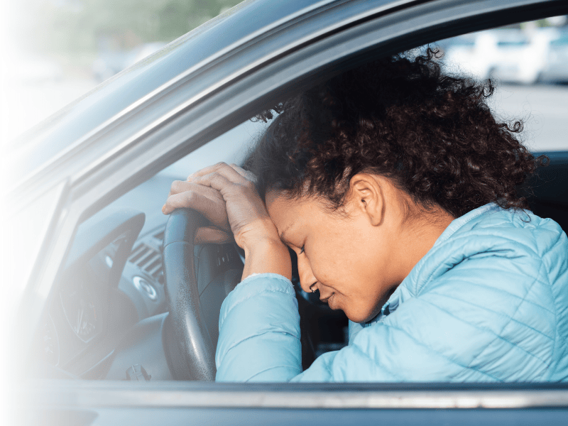 Frau lehnt sich traurig auf Lenkrad