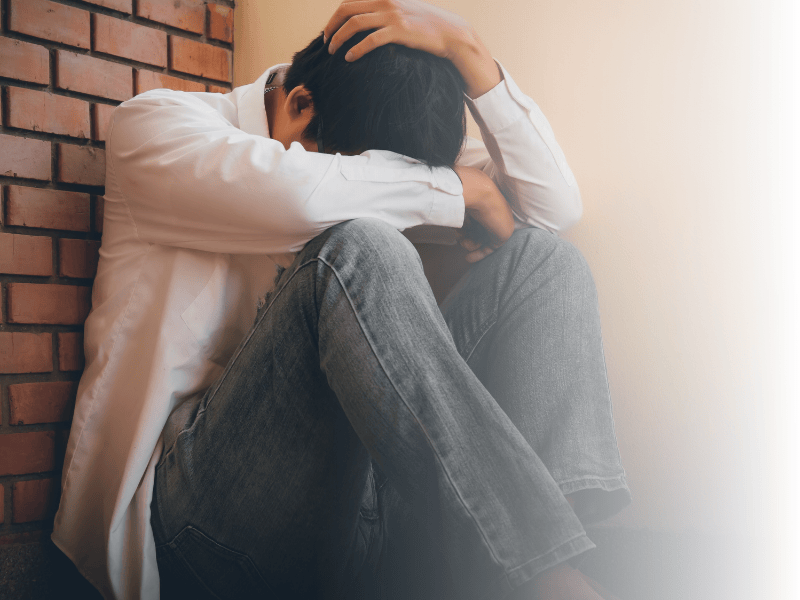 Trauriger junger Mann sitzt an der Wand