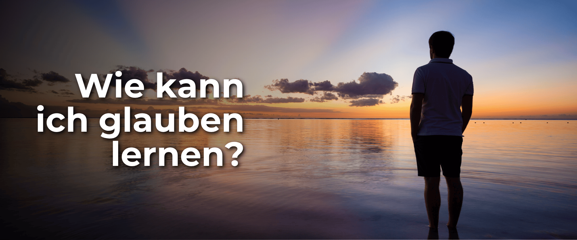 Mann schaut am Wasser auf den Abendhimmel