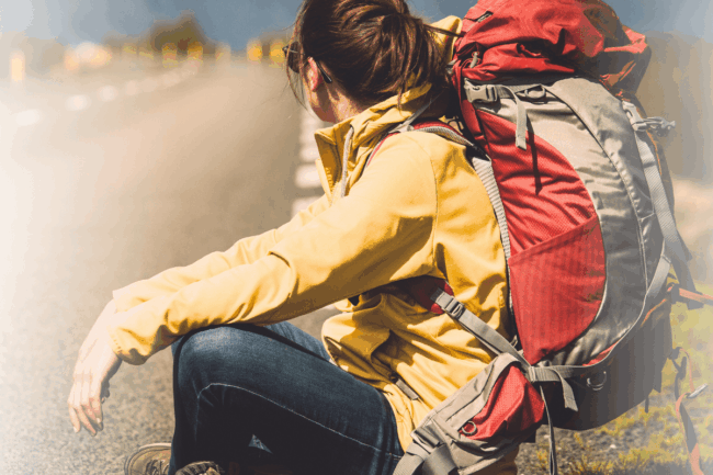 Frau sitzt mit großem Wanderrucksack