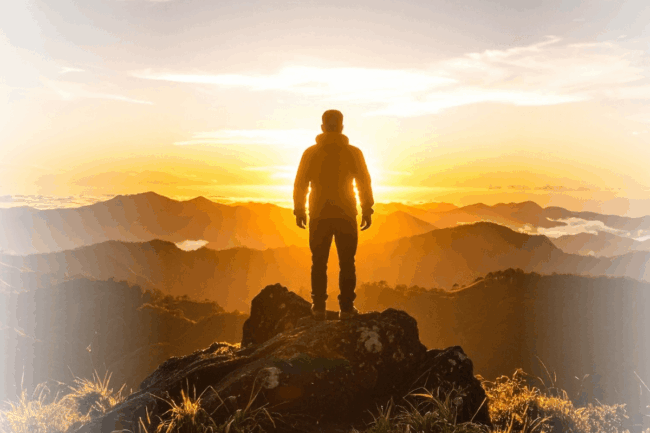 Mann steht auf dem Berg und schaut in die Abendsonne