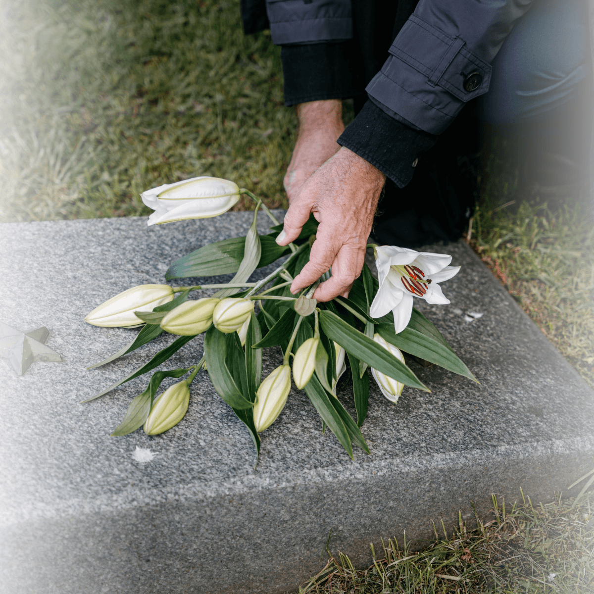 Eine Person legt Blumen auf einen Grabstein